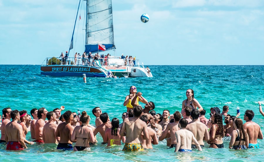 College students having fun and the Spirit of Lauderdale on their background