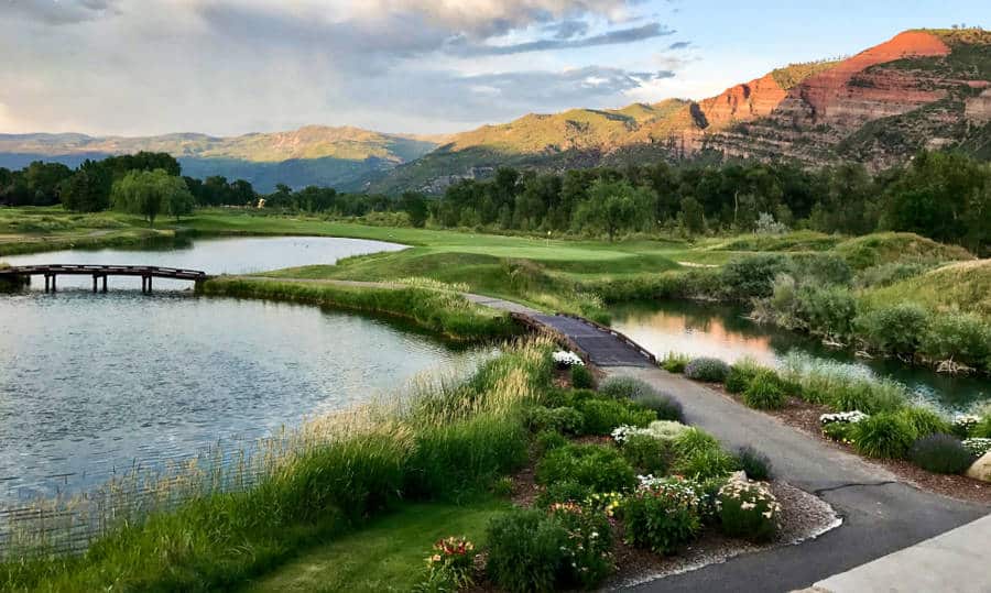 Sunset over a golf course near the lake with red rock cliffs in the background