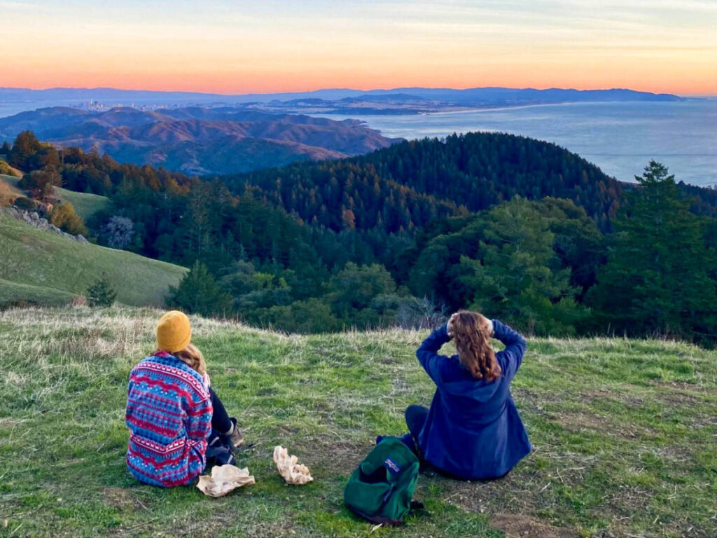 Women enjoying the picturesque view of the sunset over the hills