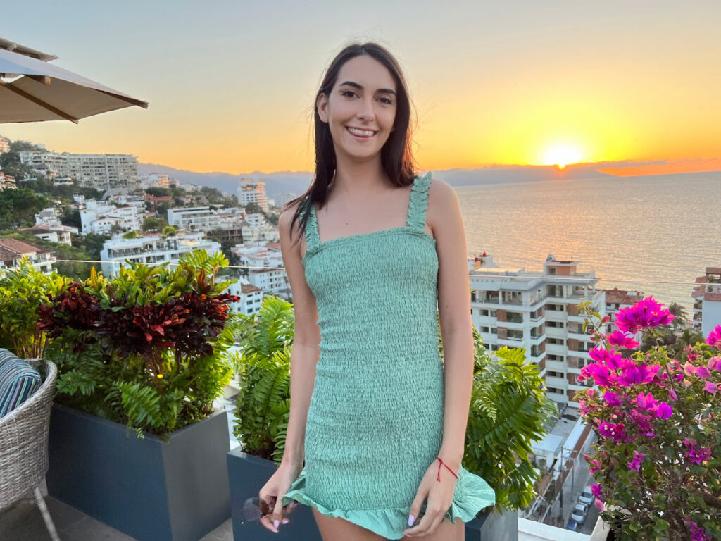 Clara posing for a photo against sunset views from the Chici tini rooftop bar