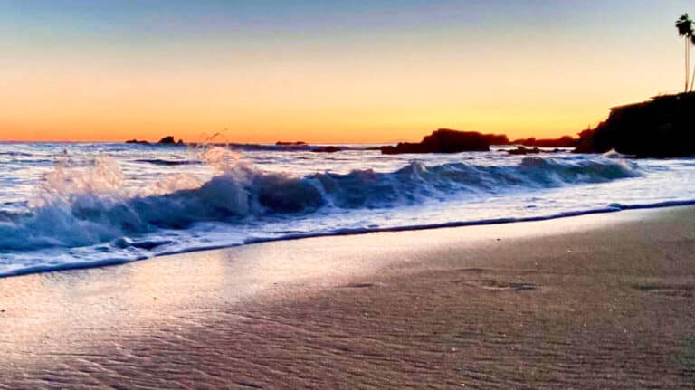 View of the waves crashing against the shore during sunset at one of the best places for where to stay in Orange County California