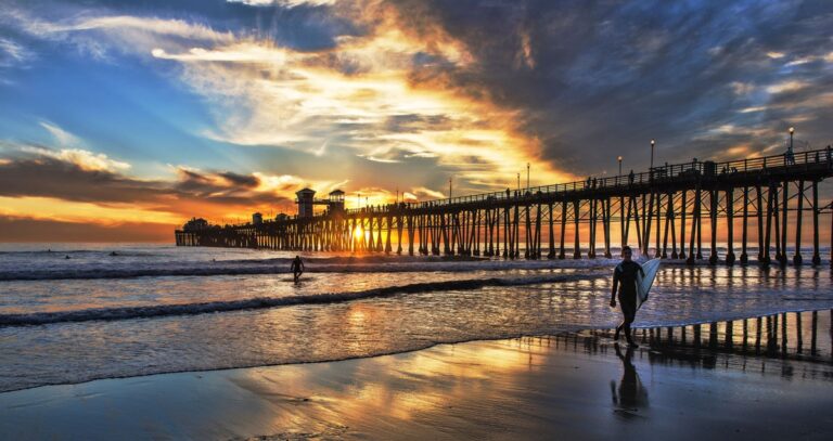 View of a surfer walking on the shoreline during sunset in San Diego