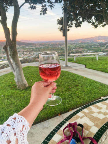 The author, Jess Levy holding a glass of wine at the Sunshine Mountain Vineyard during sunset