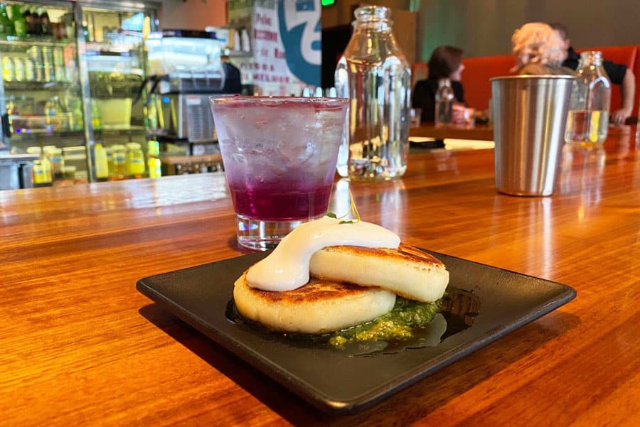 Arepas de Queso on a plate and a glass of beverage in SuperMegaBien