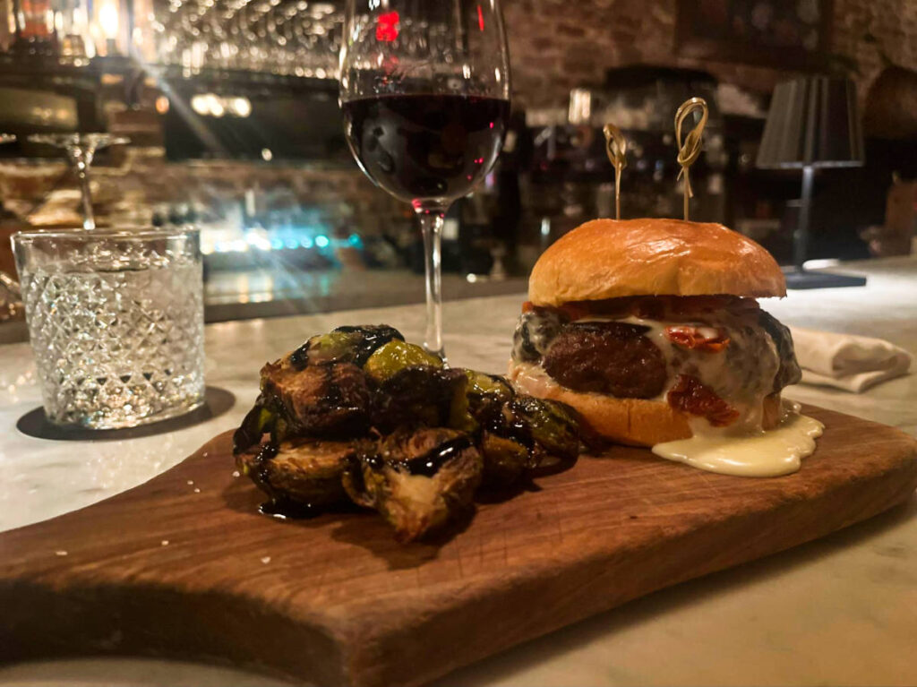 The Suprema burger with melted cheese and roasted brussel sprouts balsamic glaze on the wooden board