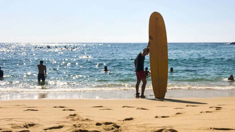 A surfer holding his surfboard at the beach