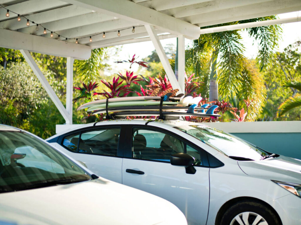 Two white cars with surfboards piled on the roof