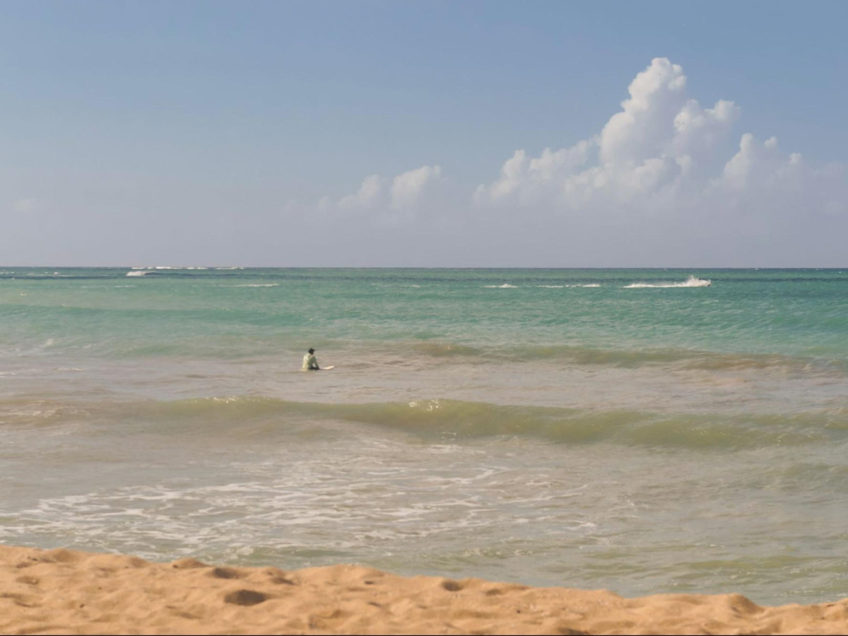 A surfer sitting at the beach waiting for the waves