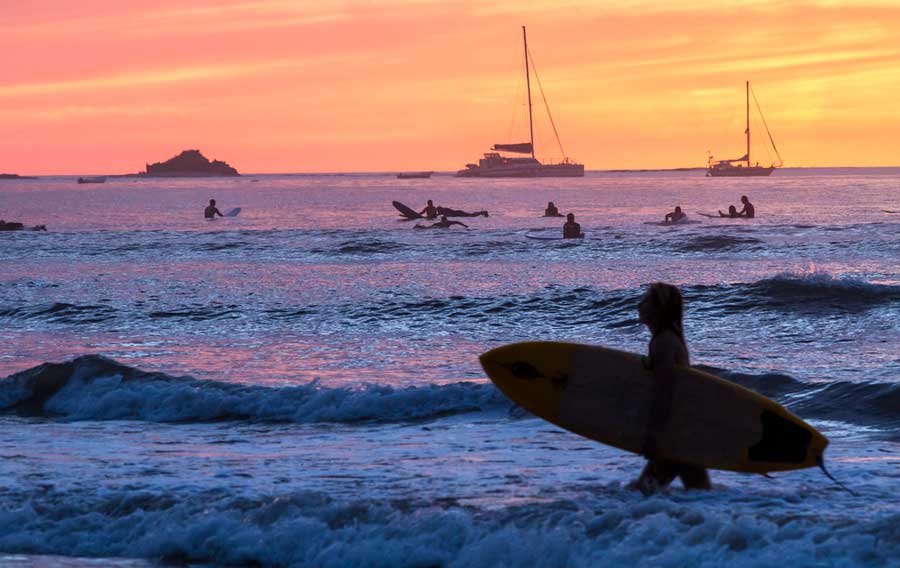 View of surfers in Playa Tamarindo during sunset