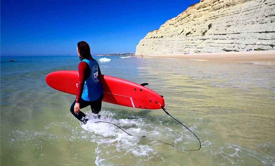 A woman carrying her surfboard in Portugal