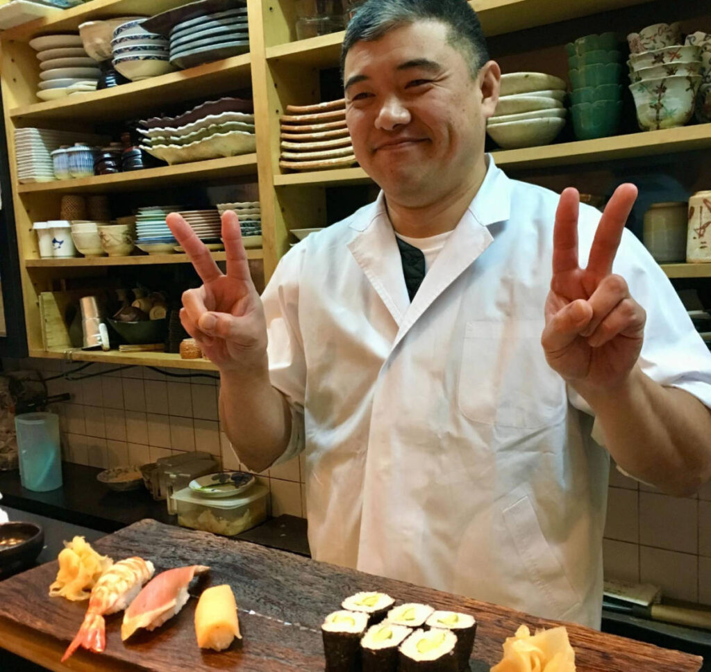 A sushi maker posing for a photo on a restaurant