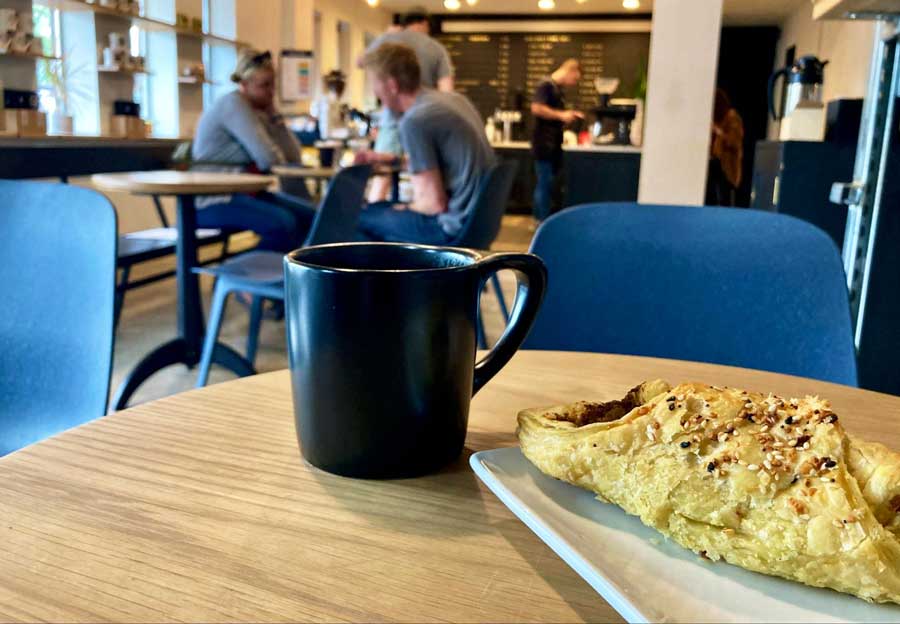 A pastry on a plate and a cup of drink in Sweet Bloom Coffee Roasters