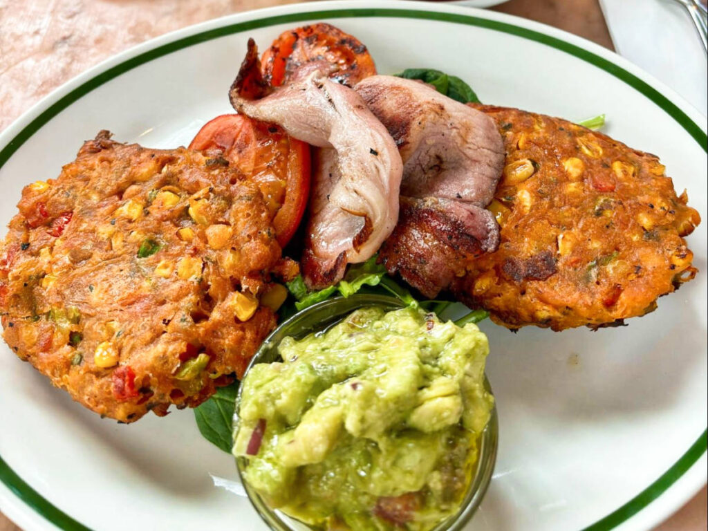 A plate with of crispy sweetcorn fritters with bacon and avocado salsa