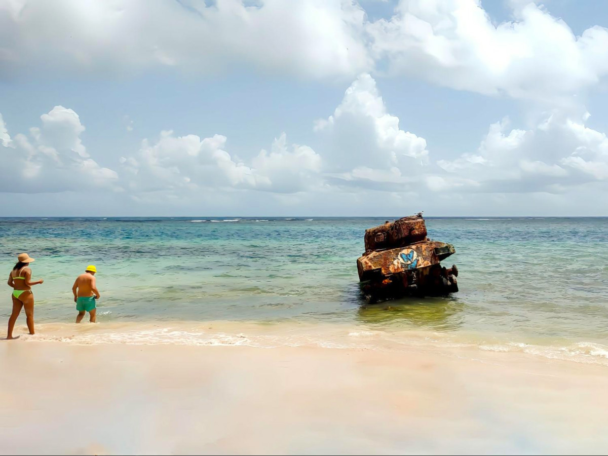 Couple walking on Flamenco Beach near an abandoned rusted tank
