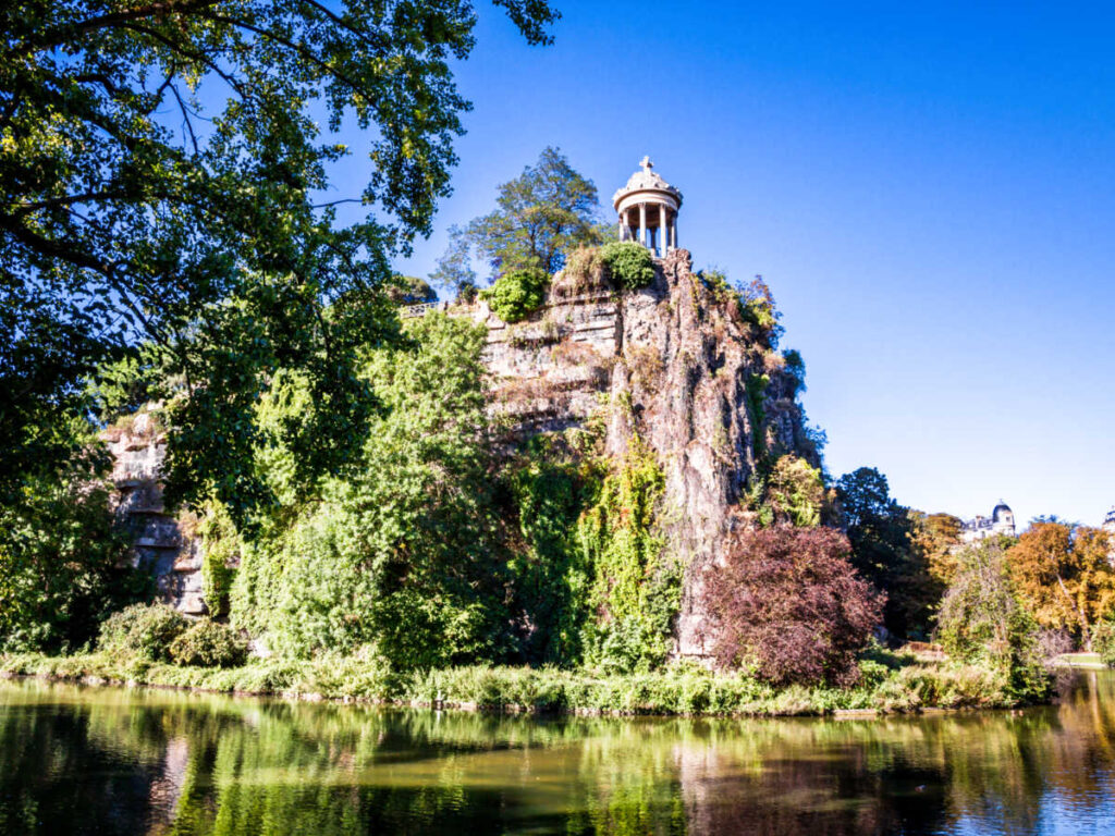 View of the Sybille's Tower above the lush rocky mountain in Buttes Chaumont Park