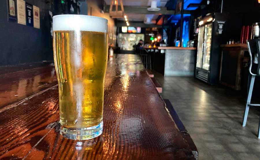 A glass of beer on a table inside TRVE Brewing Company