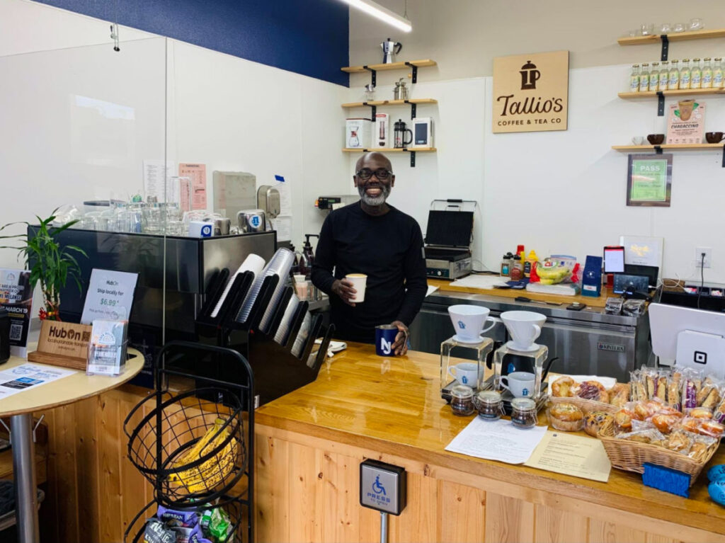 Owner of Tailio’s Coffee & Tea smiling brightly while preparing coffee