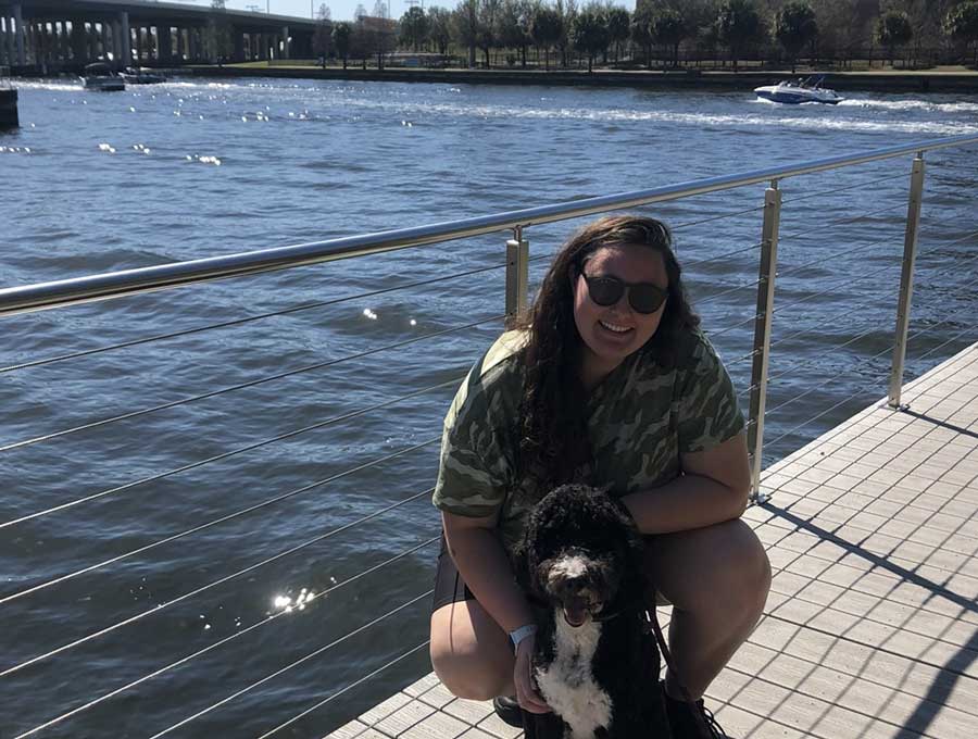 The author Marina Martinelli and her dog squatting on the walkway in Tampa Riverwalk