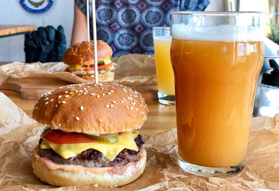 A glass of beer and a burger on a table in Taos Ale House