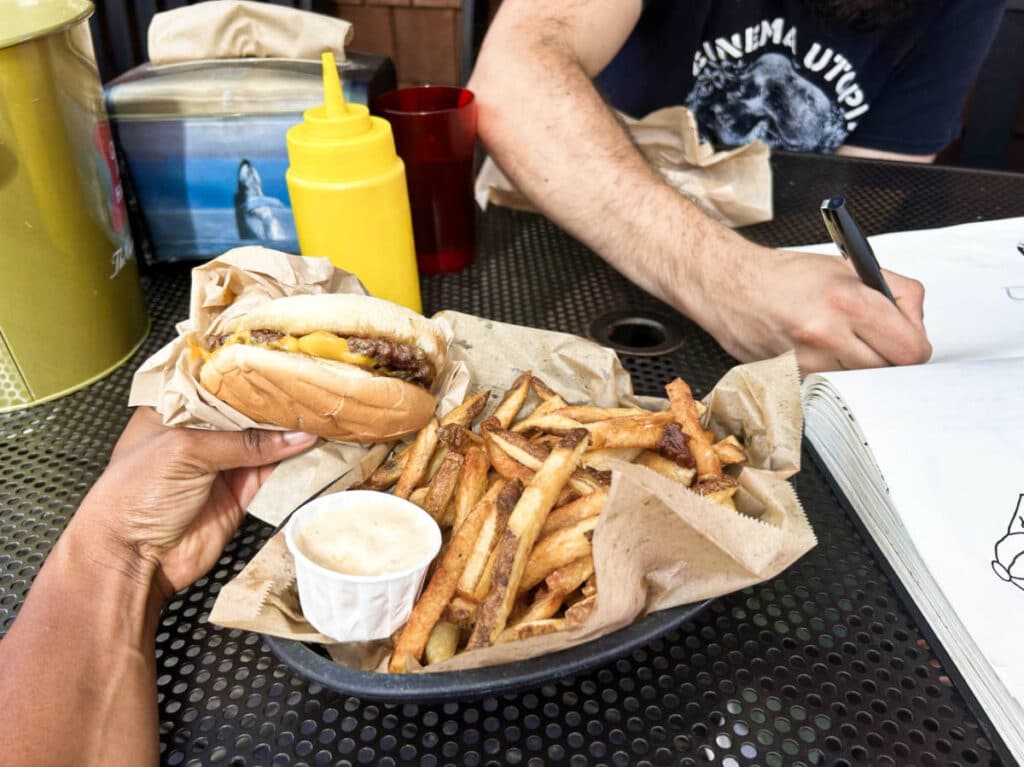 A hand holding the the basic tavern burger and a tray of fries from Loretta’s Northwesterner