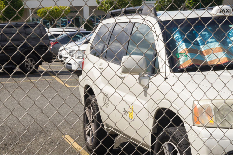 View of a white taxi through the fence