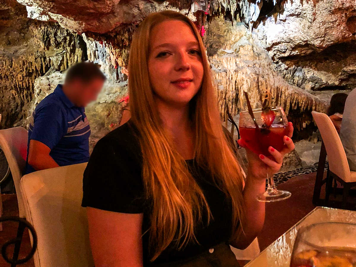 The author Taylor Herperger, holding a glass of drink in a cave