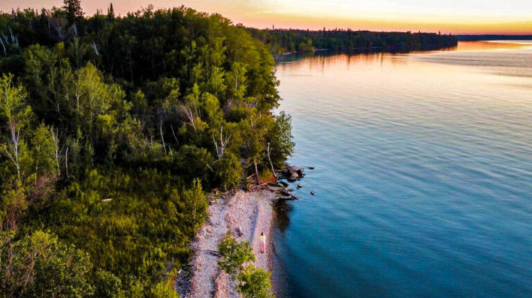 Aerial view of the author Taylor Herperger, walking along the shoreline surrounded by greenery at Grindstone Provincial Park