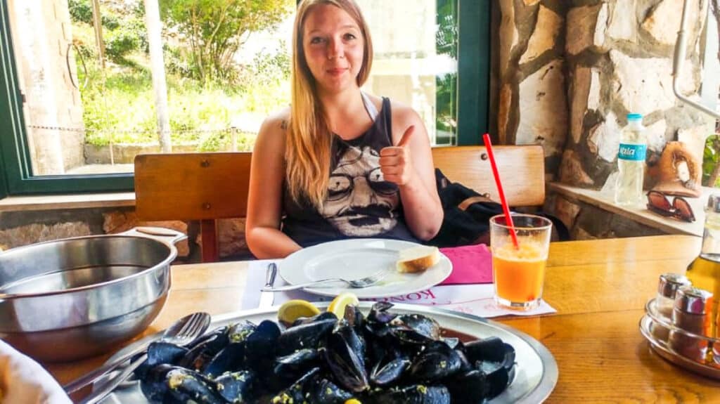 The author Taylor Herperger, posing with a thumbs up and a big serving of mussels on the table at a restaurant in Mljet Island