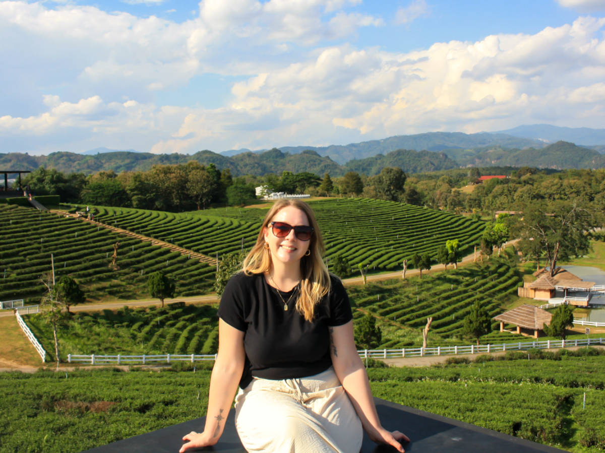 The author Taylor Herperger, sitting at the viewpoint with the vast Choui Fong Tea Plantation in the background