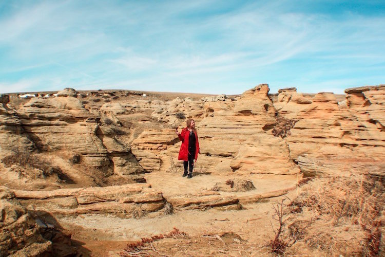 Taylor stands among red rock hoodoos in Writing-On-Stone Provincial park in Alberta