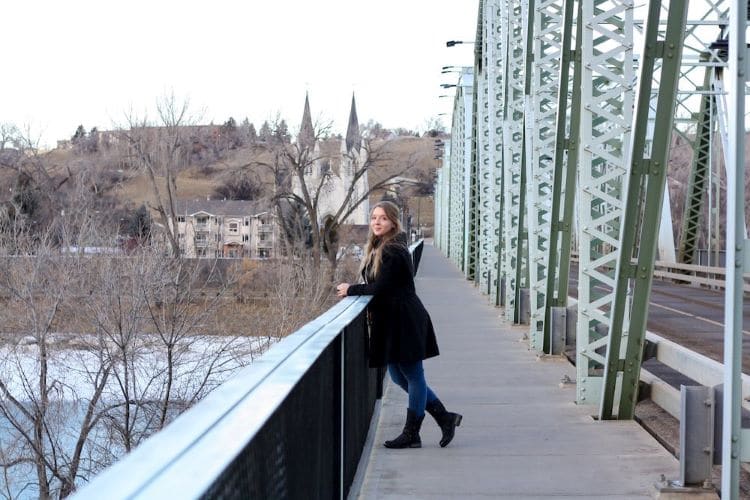 Taylor stands on a bridge with a church in the background in the city of Medicine Hat, Alberta