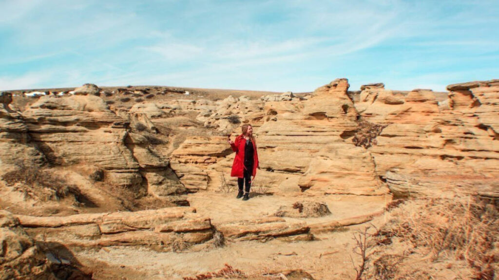 The author Taylor Herperger posing for a photo in the middle of the rock formations in Writing-On-Stone Provincial Park