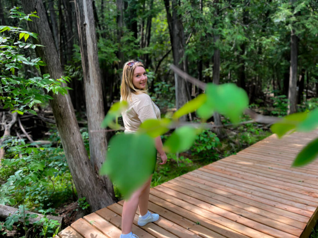 The author Taylor Herpeger, posing for a photo on the boardwalk behind the leaves
