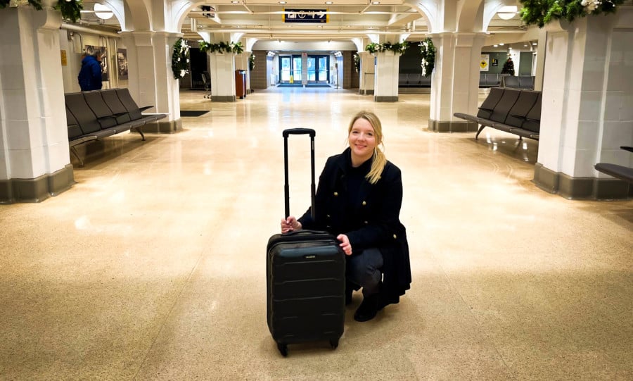 The author Taylor Herperger holding the Samsonite Omni PC Spinner Carry-On while squatting in the middle of the pathway