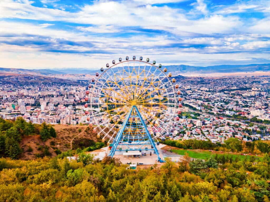 Aerial view of the giant Ferris wheel in Mtatsminda Park with the cityscape in the background
