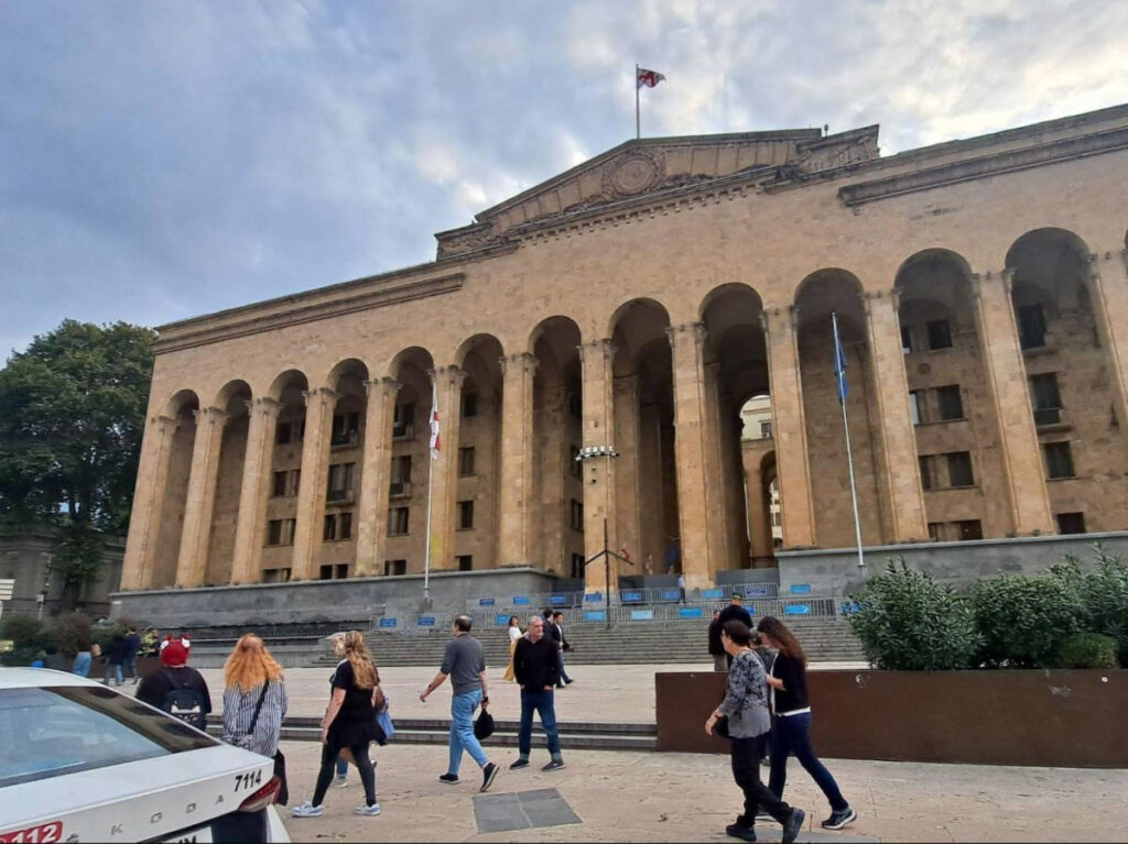 People walking in front of the Tbilisi Parliament Building