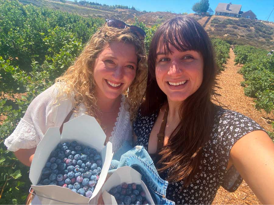 The author with her friend holding a box a blueberries that they picked in Temecula Berry Co.