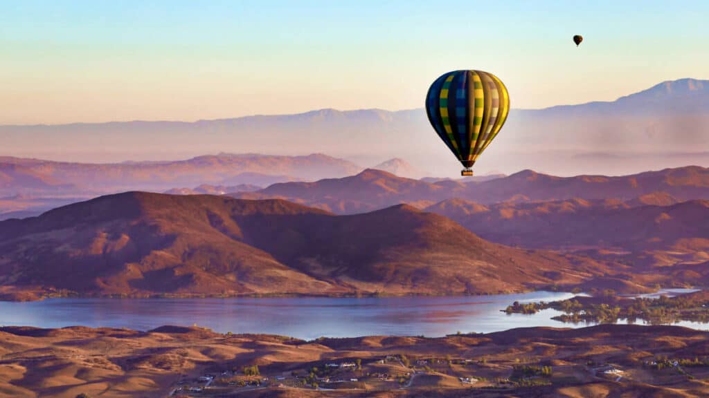 Aerial view of the Temecula Mountains, vineyards, Skinner Lake and hot air balloons over the sky at sunrise