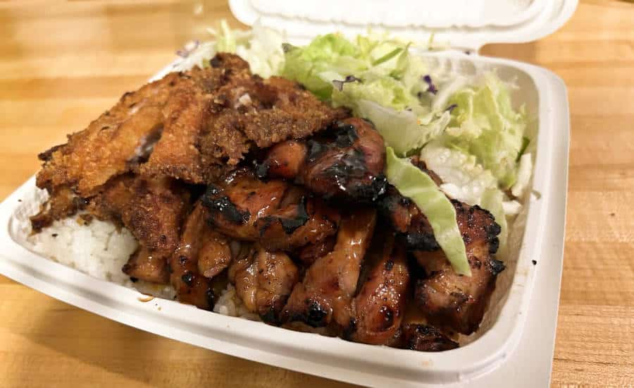 A disposable container with rice topped with teriyaki-katsu combo and vegetables