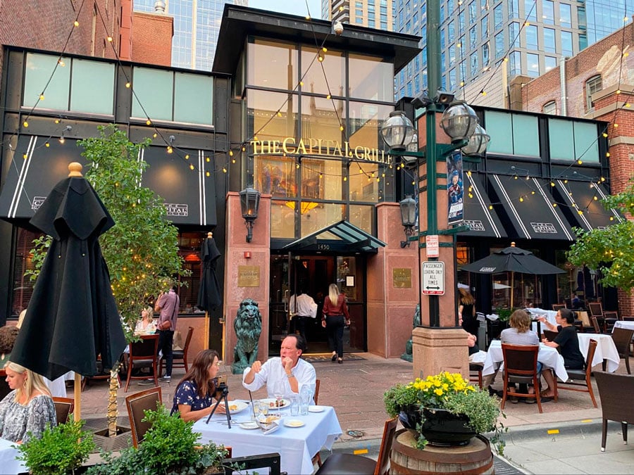 People enjoying their food on the outdoor dining area in The Capital Grille