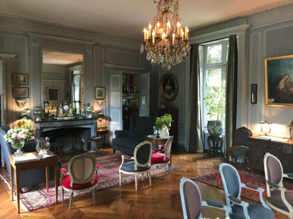 Living room in Château de Saint-Paterne with a fireplace, chairs, and a chandelier