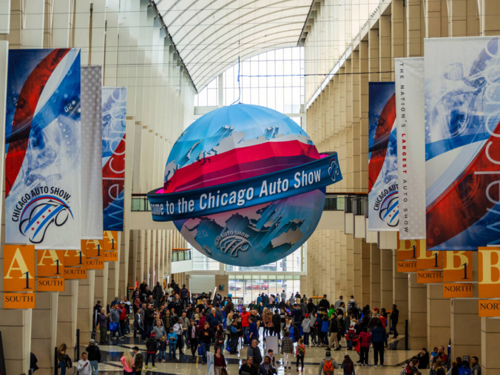 People attending the Chicago Auto Show with the Welcome to the Chicago Auto Show ball above them