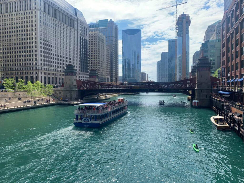 A boat glides along the Chicago River, surrounded by the city's skyline
