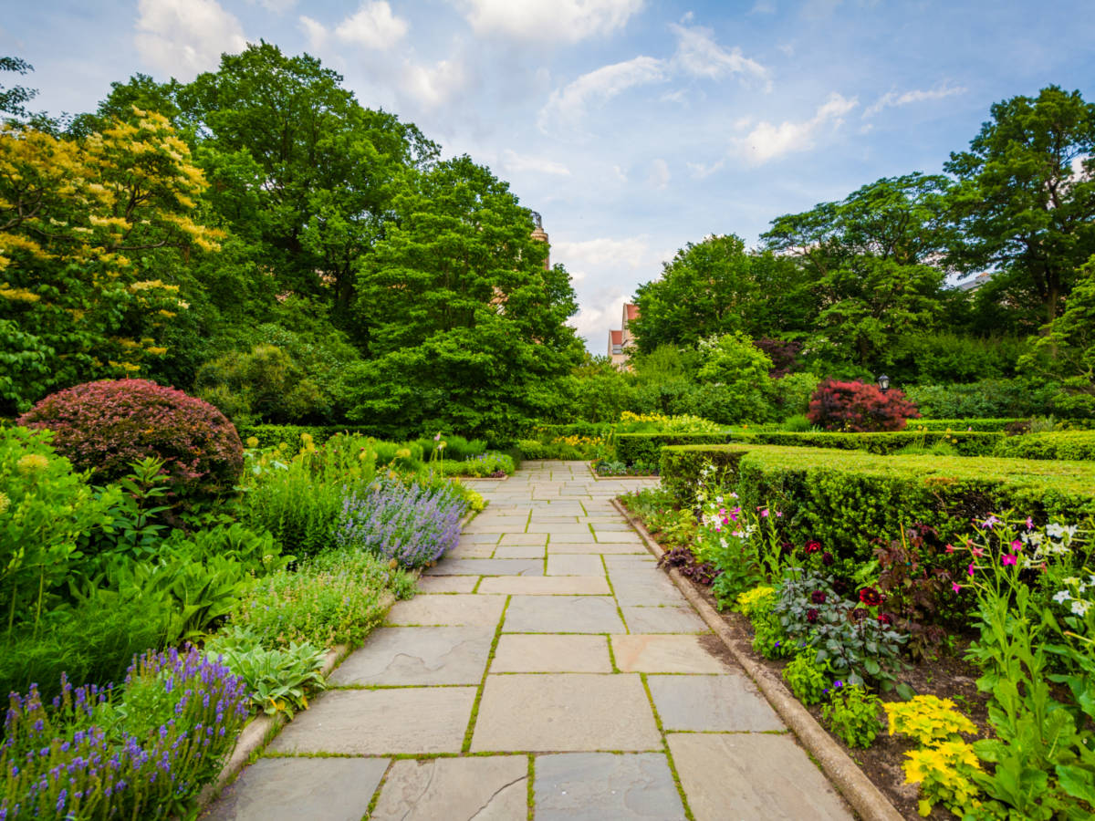 A stone pathway surrounded by greeneries at The Conservatory Garden in Central Park