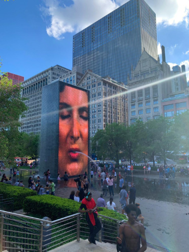 Crowd of people looking at The Crown Fountain featuring a woman's face spouting water