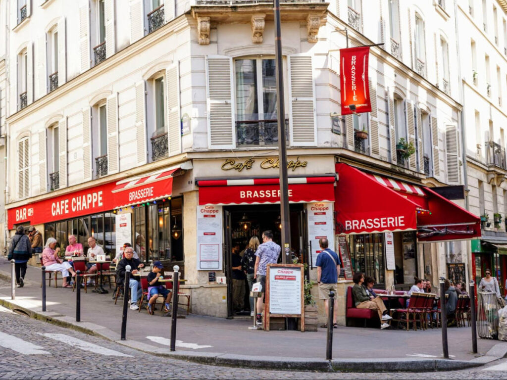 View of people dining outside The Deux Moulins Café from Amélie
