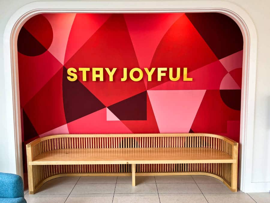 View of the red geometrical mural at the back of a wooden chair