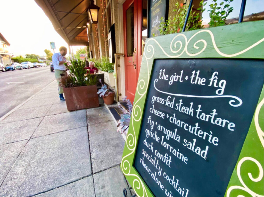 A man and a menu of The Girl & the Fig outside