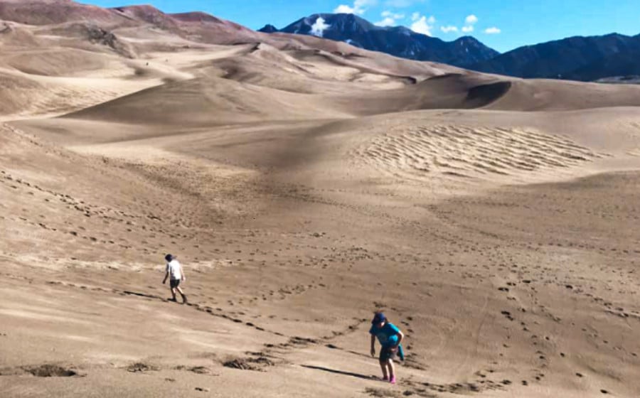 View of the people walking along The Great Sand Dunes on a sunny day