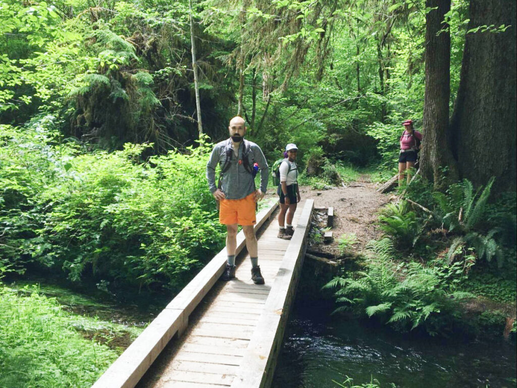 The author, Chelsea Booker with her husband crossing a bridge at the Hoh Rainforest in Olympic National Park